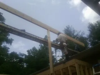 Carpenter setting a ridge beam over a new addition frame — Ice Dam Removal by Roofing Brothers in Saint Peters