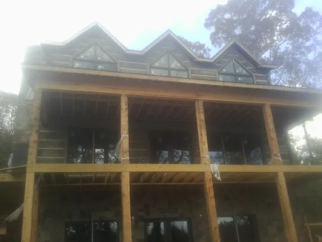 Dormers and porch framing on a large log home under construction — Roof Coating work by our crew in Saint Peters