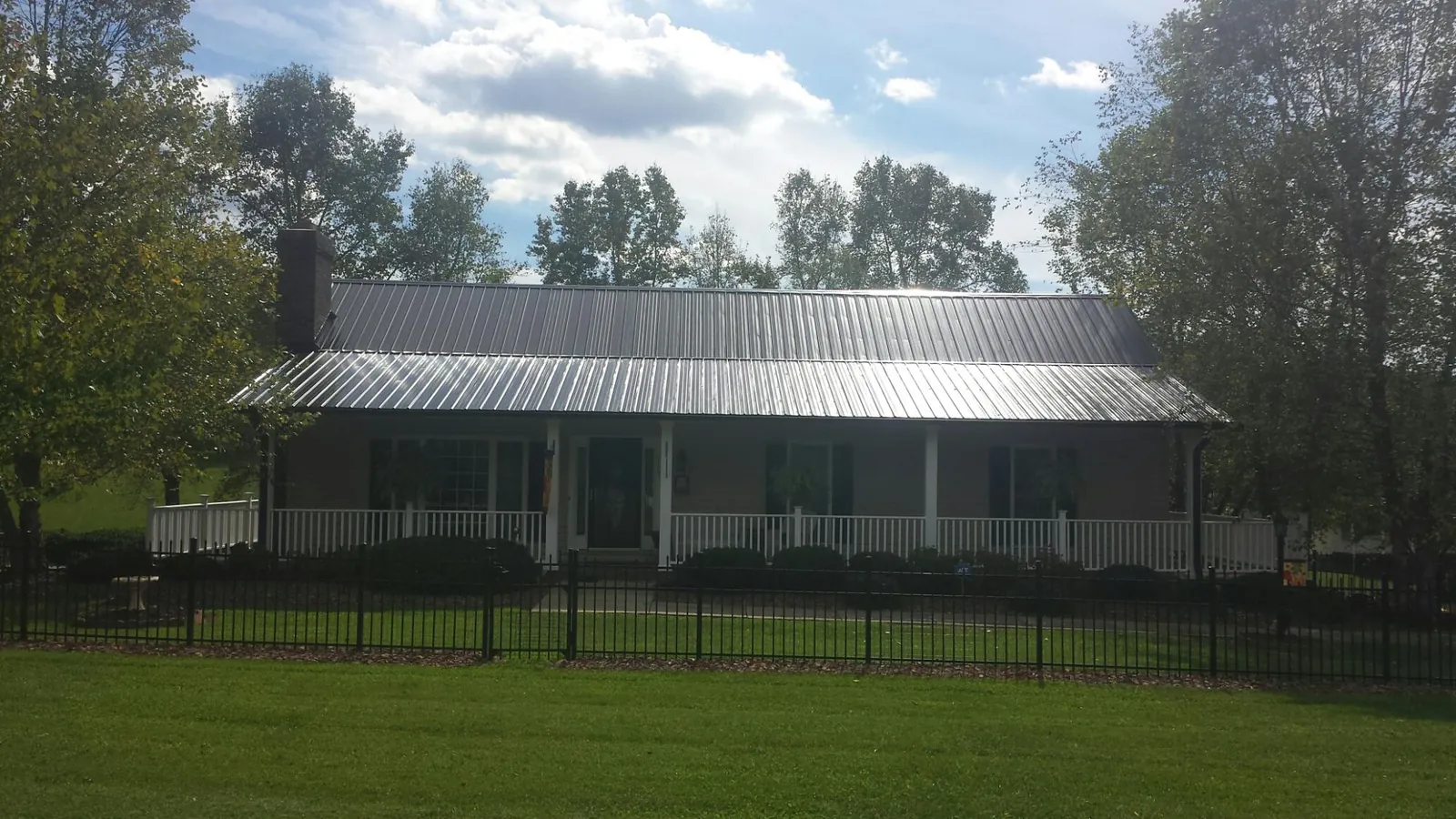 Gray metal roof on a brick ranch with a full width front porch — Gutter Guard Installation work by our crew in Saint Peters