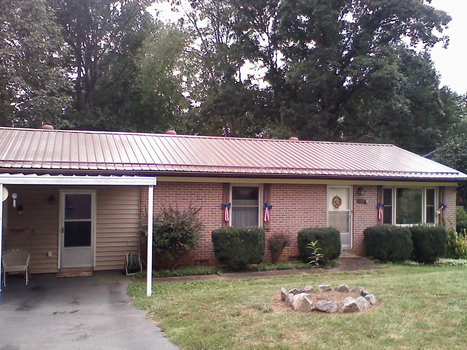 Bronze metal roof and carport on a brick ranch home — Roof Repair work by our crew in Saint Peters