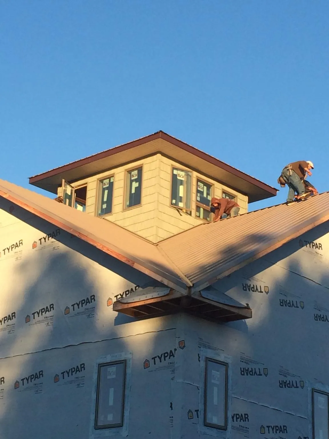 Roofers working around a rooftop cupola on a new metal roof at sunset — Roof Waterproofing in Saint Peters by Roofing Brothers
